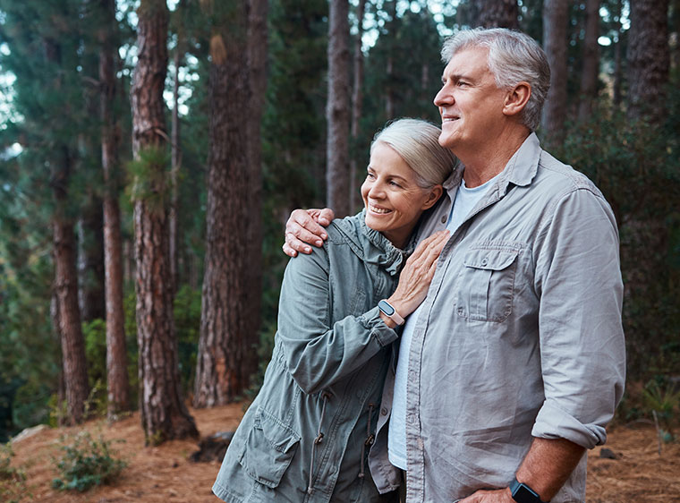 Retired couple hugging in forest